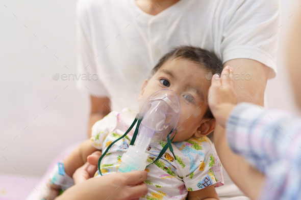 Asian little baby boy is is treated respiratory problem with vapor nebulizer in hospital admit room.