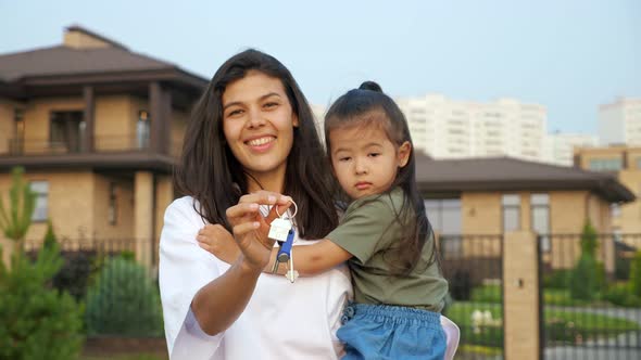 Cheerful Woman Shows Keys of Apartment Holding Daughter alt