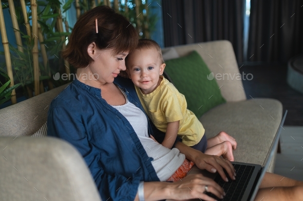 Working mom. Work from home. A mother works with her child. Video conference. Mom and her son.