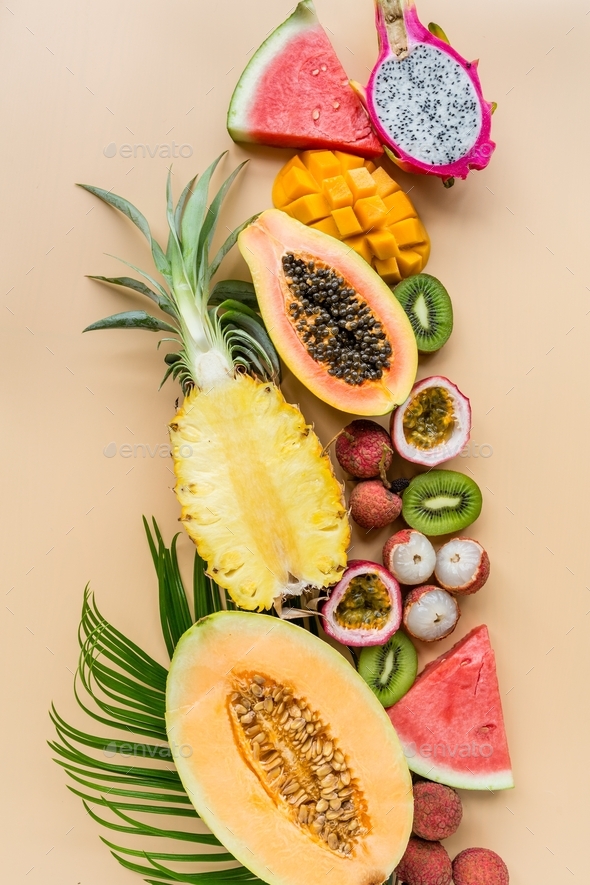 Top view of fresh sliced halves of tropical exotic fruits on orange background.