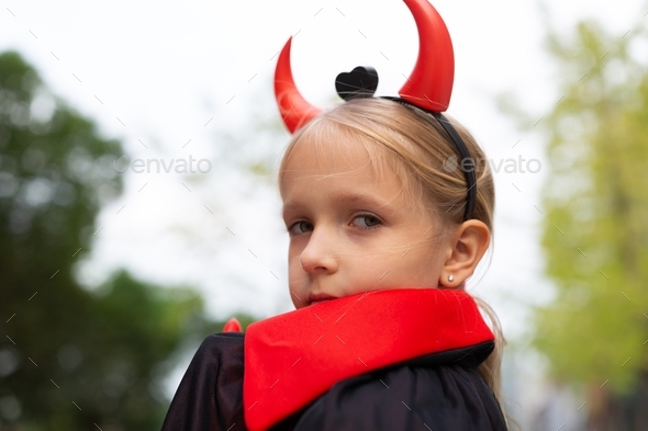 Portrait of cute Little Girl in costume of evil outdoor. Happy ...