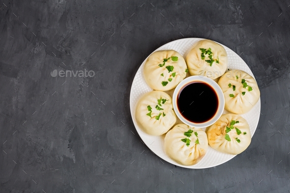 Chinese steamed dumplings baozi and soy sauce on gray concrete background with copy space