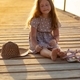 A little girl is sitting on the pier with her eyes closed - PhotoDune Item for Sale