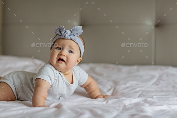 Caucasian blonde baby six months old lying on bed at home. Mockup with copy space
