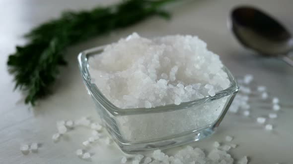 Chef with Fingers Take a Pinch of Coarse Sea Salt From the Salt Shaker on the Kitchen Table alt