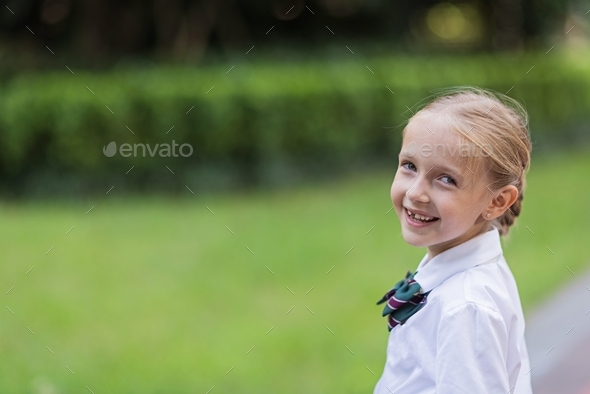 Schoolgirl back to school after vacations. Pupil in uniform smiling early morning outdoor