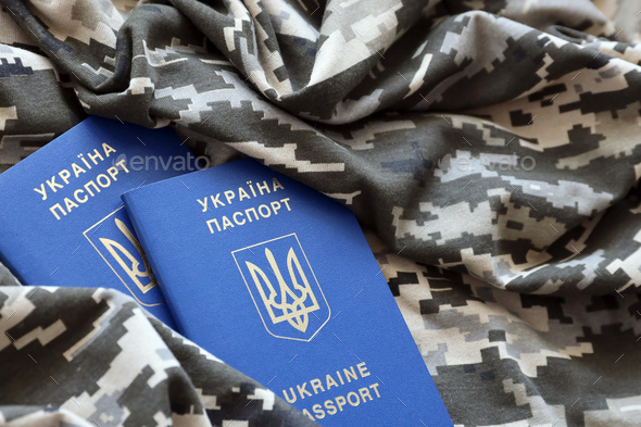 Ukrainian foreign passport on fabric with texture of military pixeled camouflage - Stock Photo - Images