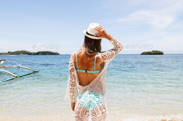 Woman from behind enjoying life and summer vacations on tropical beach on sea