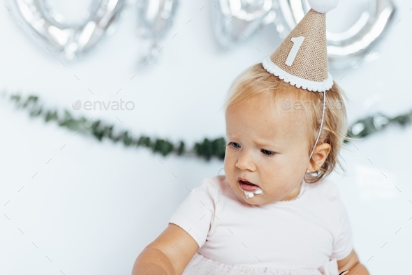 Cute caucasian baby girl with blue eyes and blonde hair one year old celebrating 1st birthday