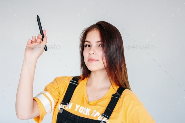 Young smiling girl student worker with dark long hair in yellow t-shirt with graphic pen in hand
