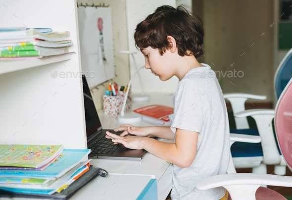 tween boy do homework learn foreign language writing in pupil book with opened laptop at room home