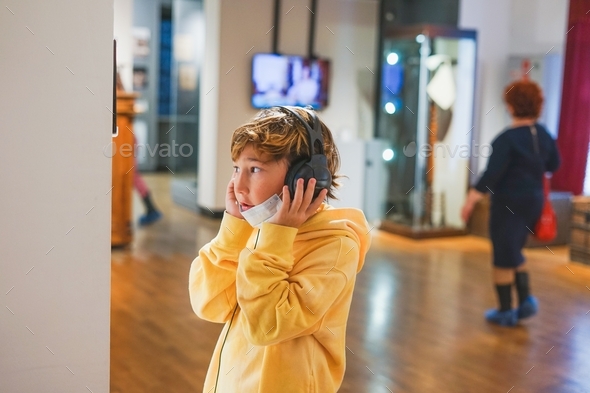 Tween boy school boy listens to an audio guide in museum