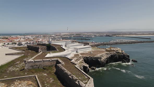 Majestic fortress on cliff with Peniche city in background, Portugal. Aerial circling