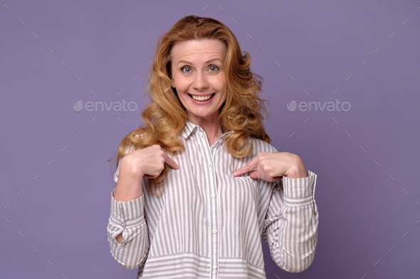 Happy charming girl with long hair bringing hands towards chest, being surprised