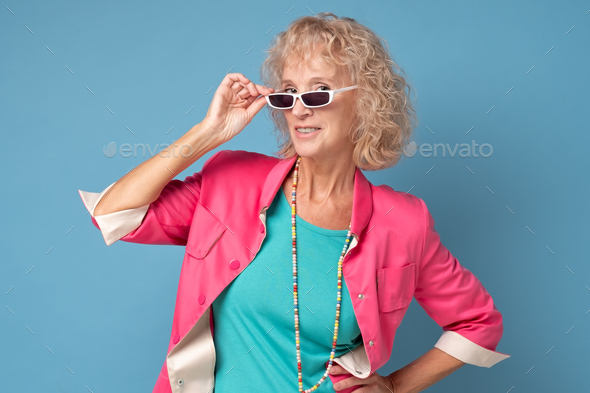 Beautiful and happy blond grandma looking at camera through summer glasses.
