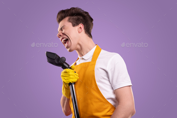 Funny man with vacuum cleaner singing in studio