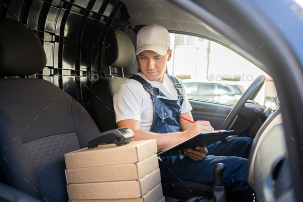 The courier driver is a male employee in a courier company delivering an order in boxes.