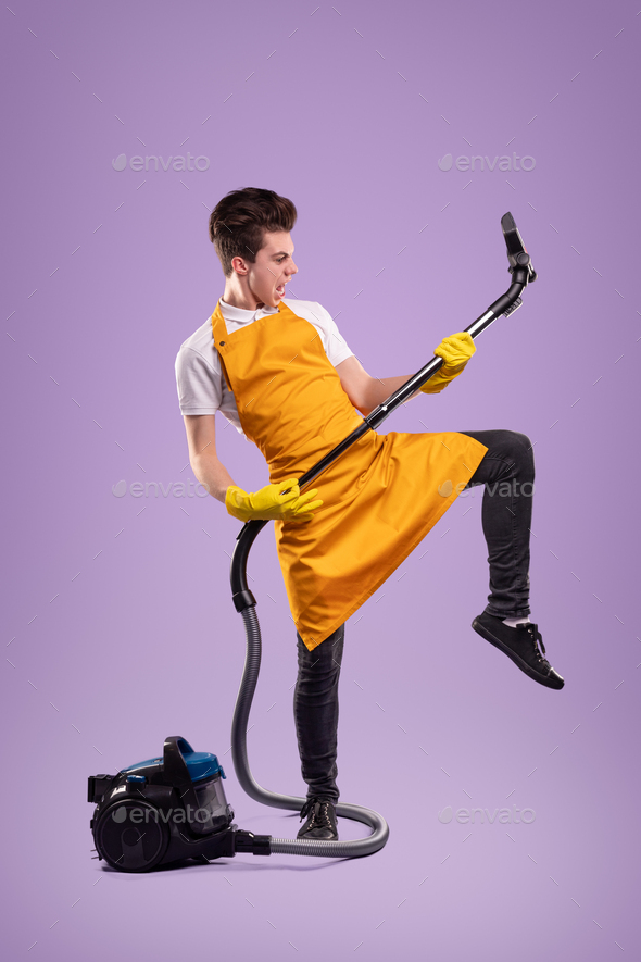 Funny housekeeper playing vacuum cleaner like guitar