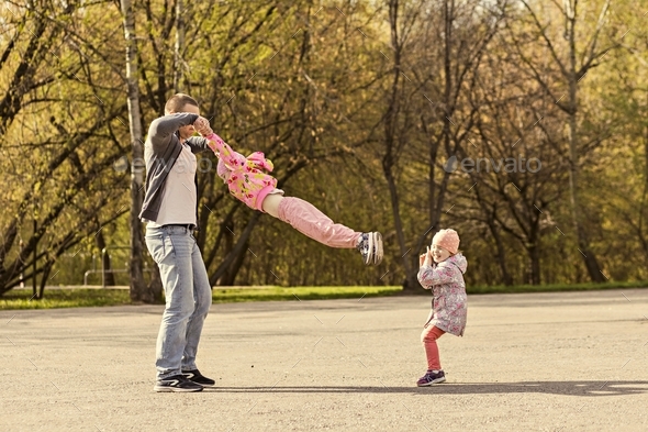 Dad plays with his daughters in the park. Twirling a girl around ...