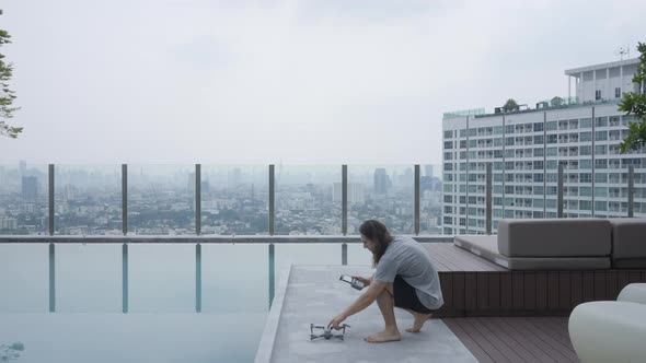 Caucasian Guy Is Setting Up His Drone Camera While In A Hotel Rooftop alt