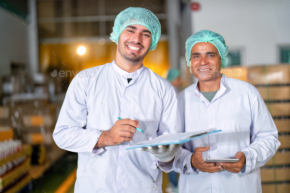 Beverage quality team in drink factory checklist stand smiling portrait near bottle stack on pallet
