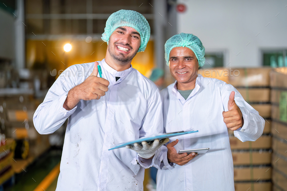 Beverage quality team in drink factory checklist stand smiling portrait near bottle stack on pallet