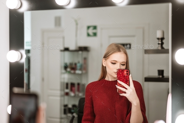beautiful young blonde woman with a beautiful evening makeup stands in a beauty salon