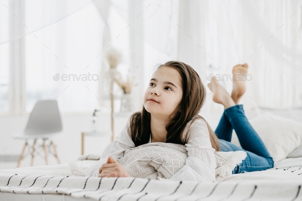 brunette preteen girl in jeans and a white shirt is resting and ...