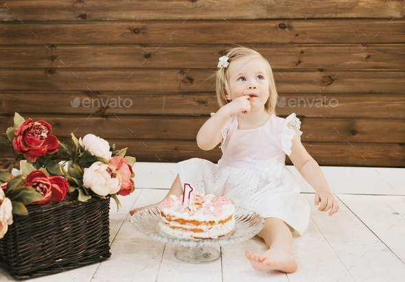 little beautiful blue-eyed girl celebrates her first birthday in the style smash a cake