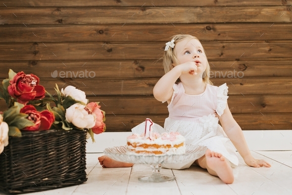 little beautiful blue-eyed girl celebrates her first birthday in the style smash a cake