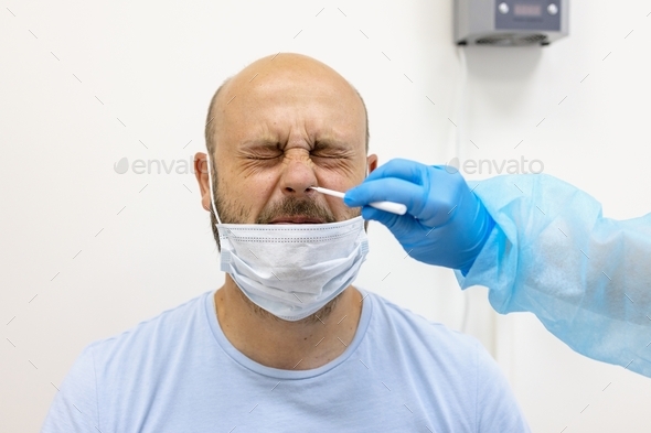 bearded man wearing protective face mask passes PCR nose swab for covid-19 in laboratory