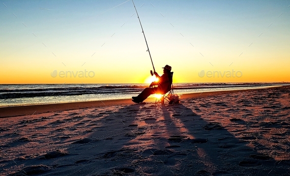 Silhouetted old man and the sea sitting on sandy beach in minimalist landscape surf fishing.