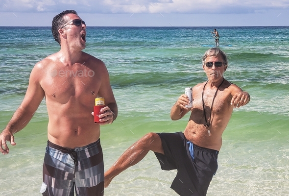 Dad trying to keep up with his hipster cool son drinking beer at the beach and goofing off.