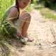 A little girl is sitting on a country road and holding a bouquet in her hands - PhotoDune Item for Sale