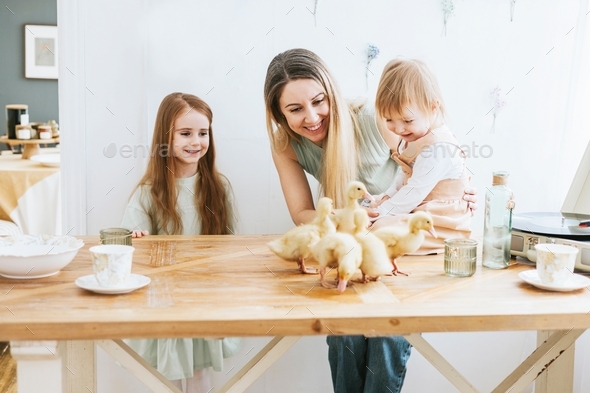 two cute little red haired girls sisters and mother young woman stand in kitchen of country house wi