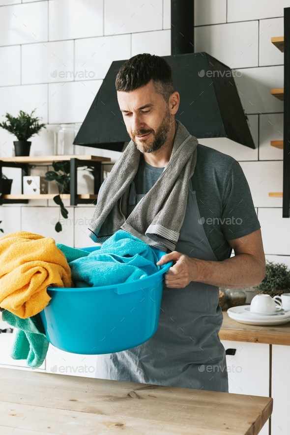 young man in apron does household chores with towel on his shoulder, men housework, household help i