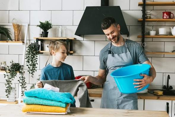 family dad young man and son teenage boy in apron do household chores, men housework, household help