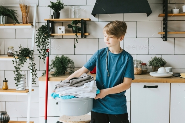 cute teenage boy do household chores, men housework, household help in stylish kitchen in modern apa