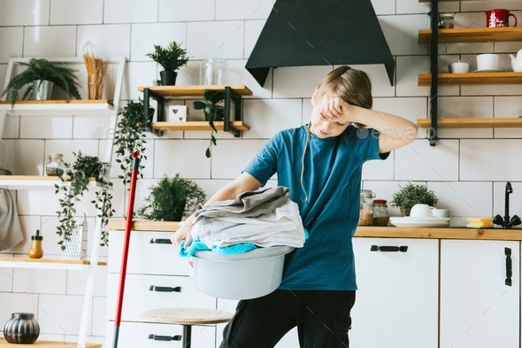 cute teenage boy do household chores, men housework, household help in stylish kitchen in modern apa