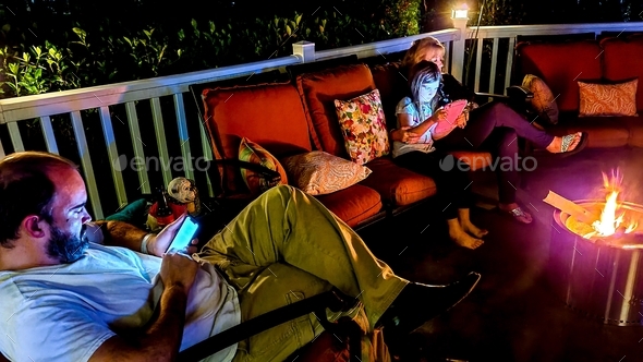 Family togetherness around the fire pit at night in winter using technology.