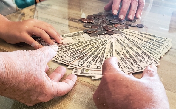 Babyboomer hands teaching grandkids the value of money bills and coins in business and finance.