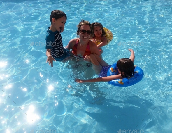 Fun-loving millennial mom in pool with her generation z kids keeping cool in summer.