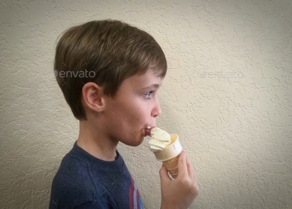 Profile of a generation z boy eating a frozen treat.
