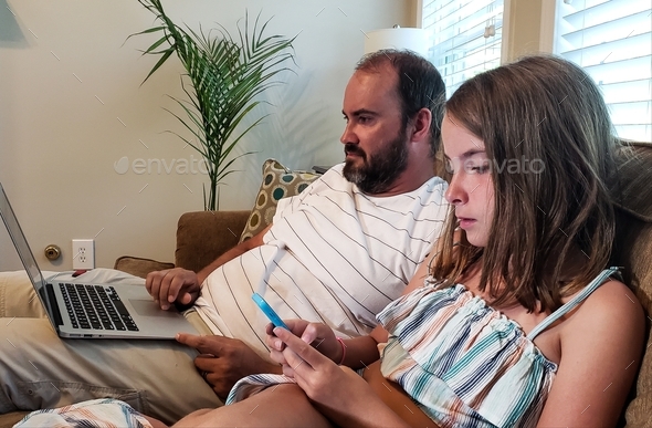 Millennial dad on a couch online shopping with his generation z daughter at home.