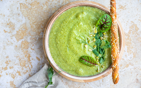 Green vegetable cream soup with micro greens, salad leaves and breadstick