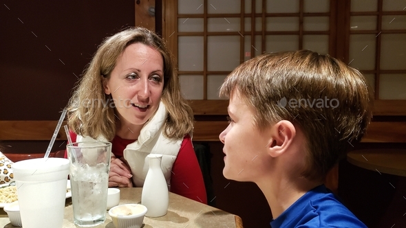 Generation z boy at table in restaurant with millennial mom having a conversation.