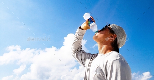 Hipstdr cool guy drinks bottled water at the beach with blue sky ...