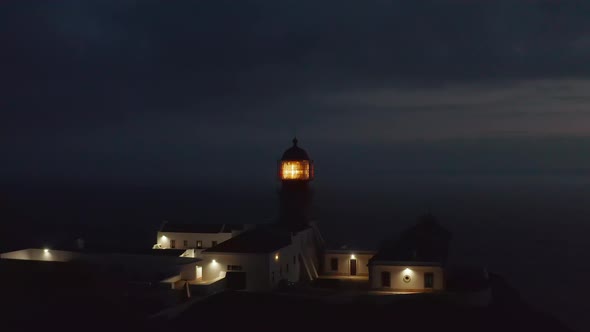 Aerial Drone Flying Forward Towards Lighthouse Shining Head Fresnel Lens in Lagos Algarve Portugal alt