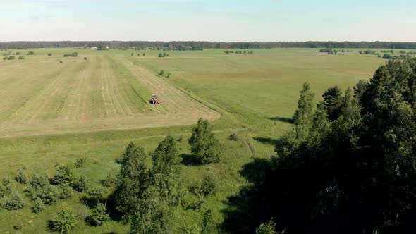 Farmer on a Combine Mows Juicy Grass for Livestock Feed on a Summer Day alt