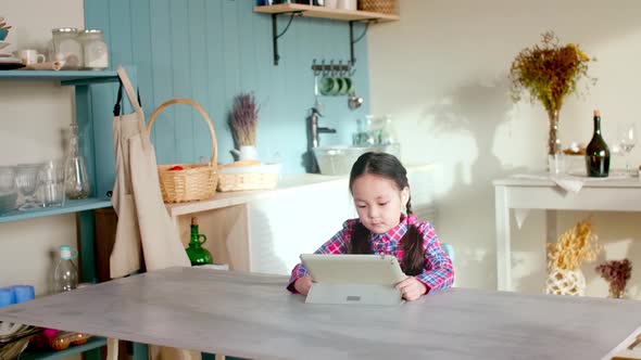 Little Asian Girl Playing on Tablet at Home